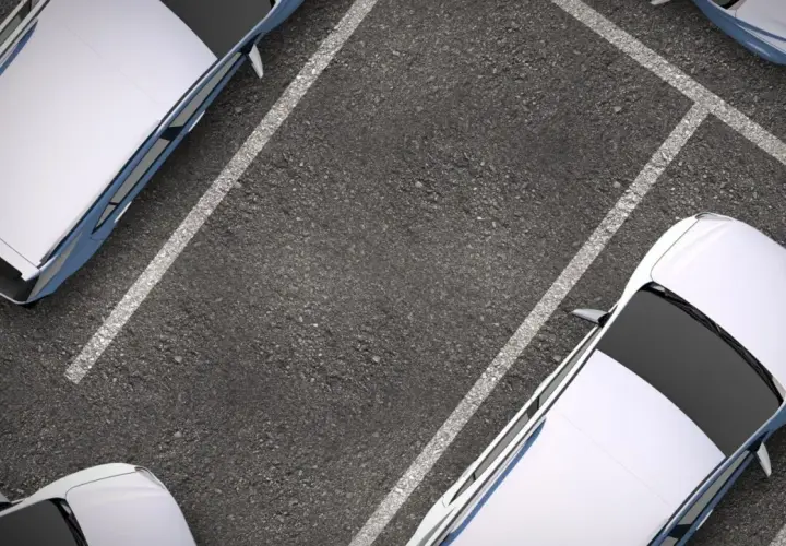 Widok z góry na miejsca parkingowe z białymi samochodami. Idealne parkowanie to sztuka.