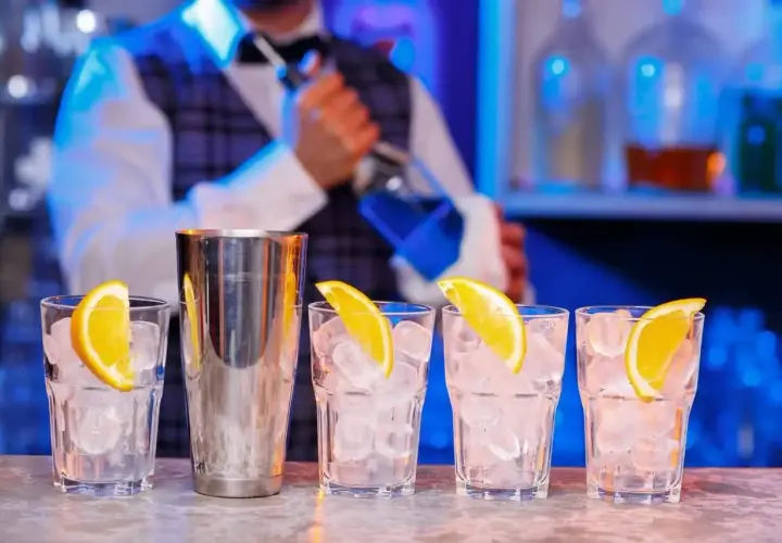 Barman przygotowuje drinki. Zastanawiasz się, ile kosztuje kurs barmanski? Zobacz, jak powstają drinki z lodem i pomarańczą.