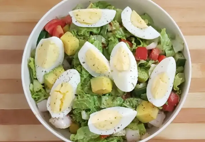 Salade colorée avec avocat, œuf dur coupé en quartiers, tomates, concombres et laitue. Un délice frais et équilibré.
