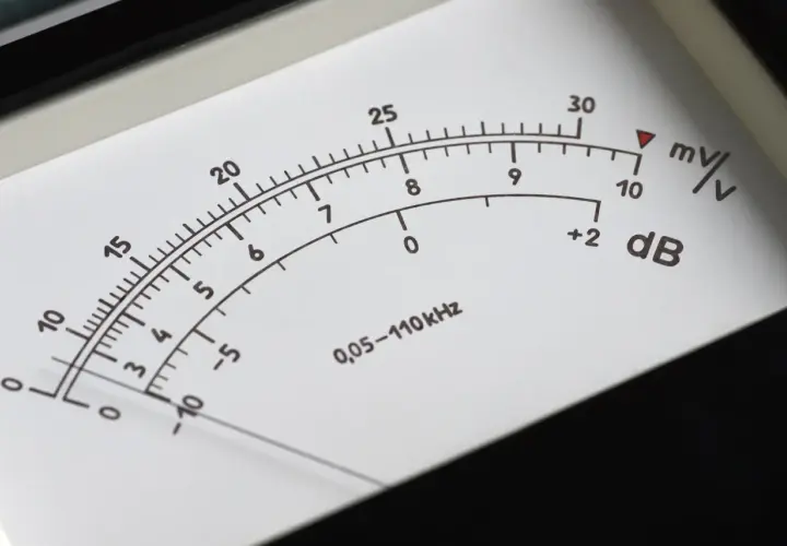 Wskaźnik miernika pokazuje poziom dźwięku w decybelach (dB). Skala obejmuje wartości od -10 do 30 dB, z dodatkowymi oznaczeniami mV/V.