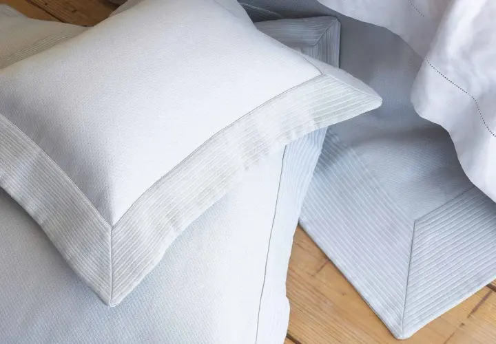 Close-up of white pillow shams with decorative borders, often used to dress up a bed and protect pillows.