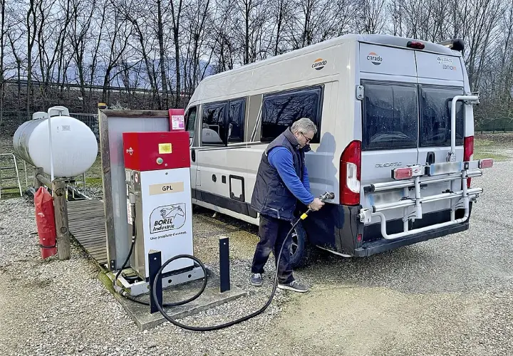 Un homme fait le plein de son camping-car à une pompe GPL. Le bon gaz pour camping car est le GPL.