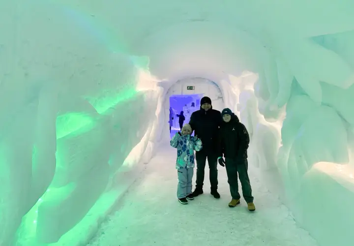Rodzina w lodowym tunelu, gdzieś w okolicy wioski Świętego Mikołaja. Ściany lśnią zielonym światłem.