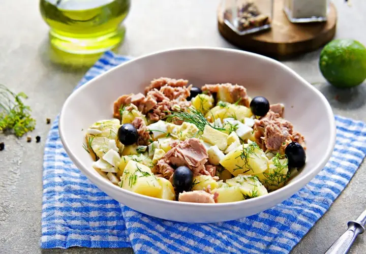 Deliziosa insalata di patate e tonno, arricchita da uova sode, olive nere e aneto fresco. Un piatto gustoso e completo.