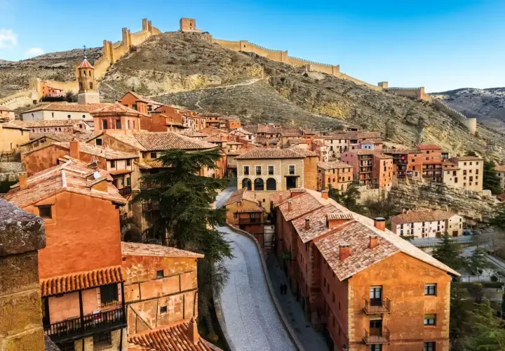 Pueblo medieval con casas de terracota y murallas en la ladera. Merece la pena visitar Teruel por su encanto histórico y vistas espectaculares.