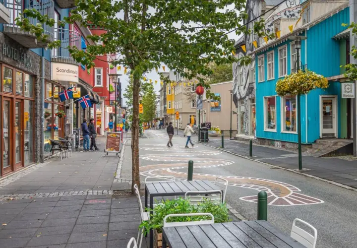 Kolorowa ulica w Reykjaviku z budynkami, flagami Islandii i artystycznymi wzorami na jezdni.