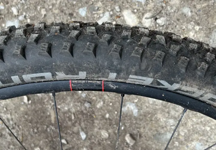 Close-up of a Schwalbe Rocket Ron tire on a mountain bike wheel, ready for a review. The tread is visible, along with rim details.