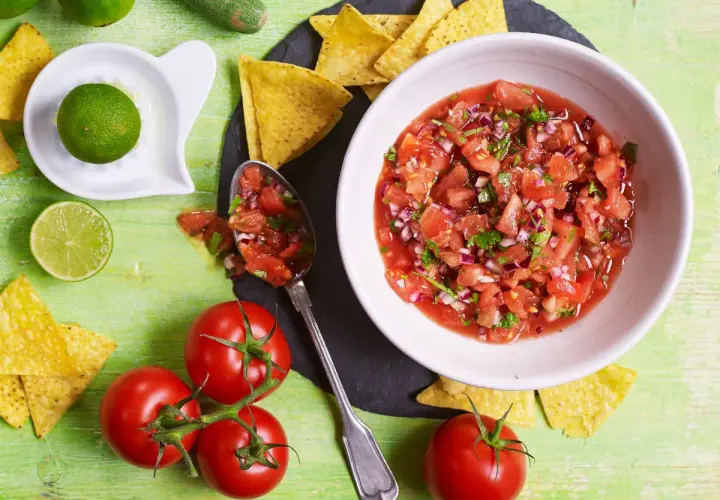 Świeża salsa pomidorowa z cebulą i kolendrą, podana z nachos i limonką. Idealna do meksykańskich potraw.