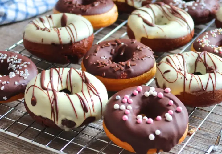 Deliciosos donuts al horno cubiertos de chocolate, glaseado blanco y chispas de colores.