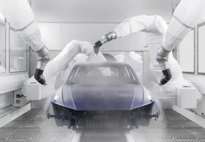 Robots pintan un coche entero en una cabina de pintura.