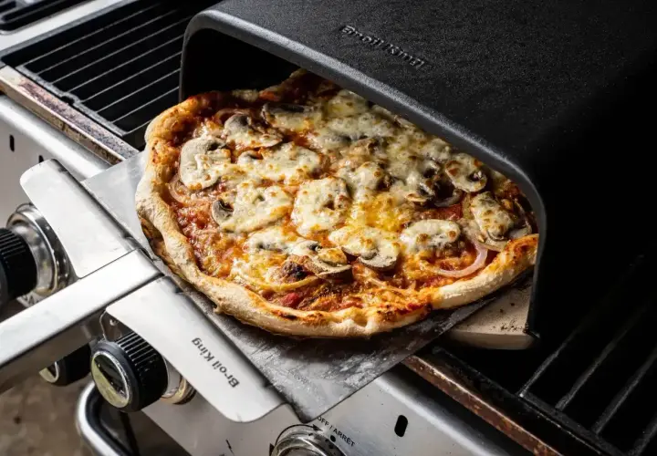 Pyszna pizza z pieczarkami i serem, właśnie wyjęta z pieca grillowego. Idealna do dzielenia się z przyjaciółmi, bo ile piec pizze, tyle radości!