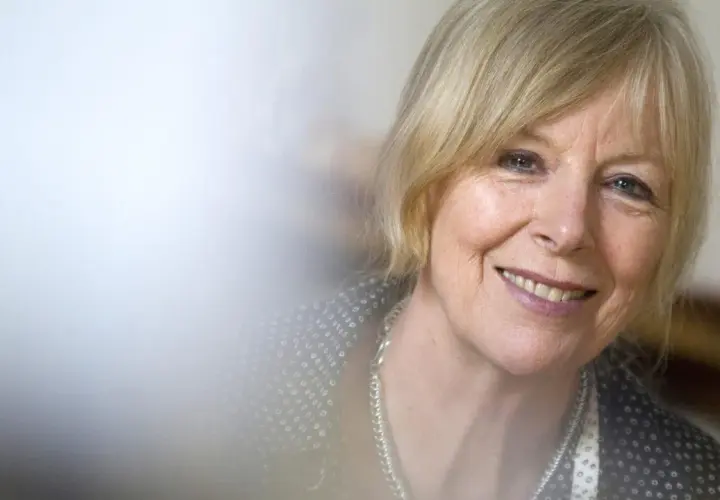Porträt von Dagmar Ploetz, die lächelnd in die Kamera blickt. Sie trägt eine silberne Kette und ein gemustertes Oberteil.