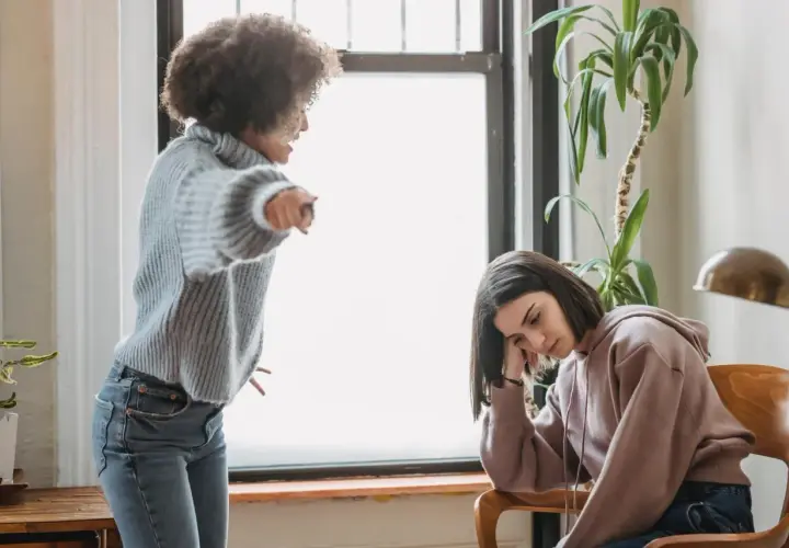 Una madre urla contro la figlia adulta, che appare abbattuta e rassegnata. Un esempio di come i genitori distruggono i figli adulti con critiche continue.