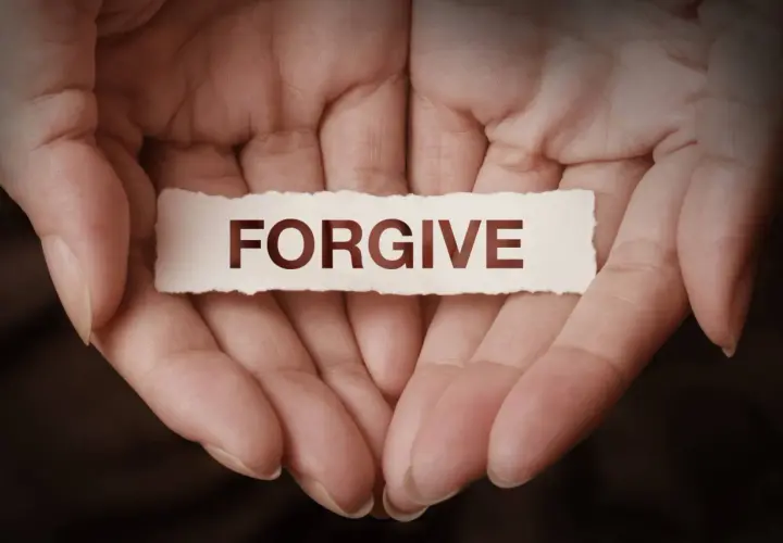 Dłonie trzymające skrawek papieru z napisem "FORGIVE". To symbol tego, co to znaczy wybaczyć – uwolnić się od urazy i otworzyć na pojednanie.