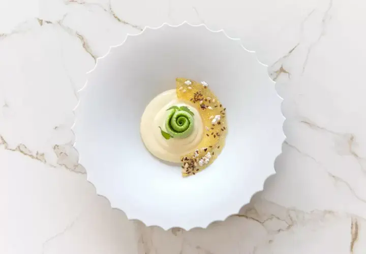 Dessert crémeux avec spirale verte, garni de fruits confits et graines.