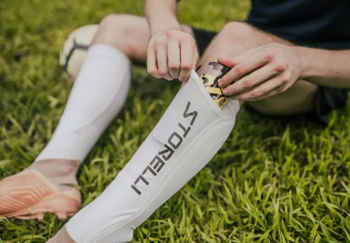 Fußballer legt ein Schienbein Splint mit Tarnmuster in eine weiße Hülle.