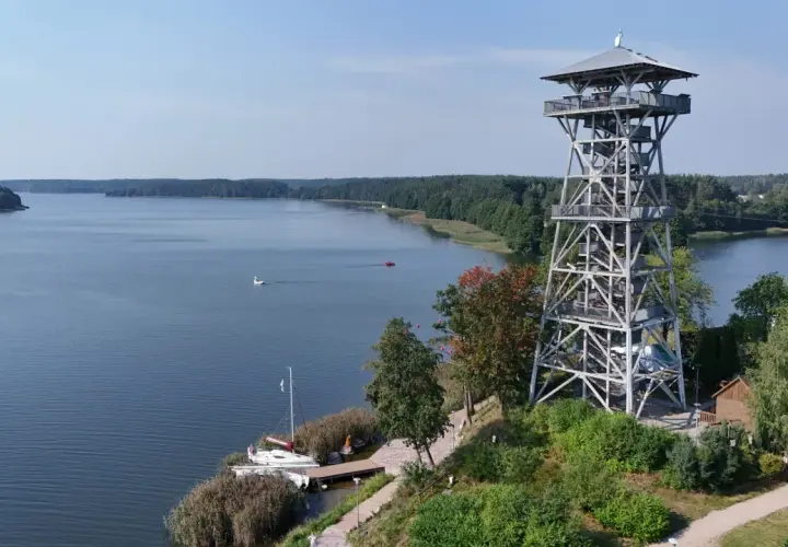 Wieża widokowa we Wdzydzach góruje nad jeziorem, oferując malowniczy widok na wodę i las.