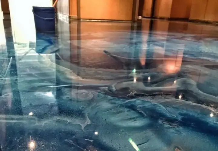 Błękitna żywica w garażu tworzy efekt fal oceanu. Widać niebieskie wiadro i odbicia światła.