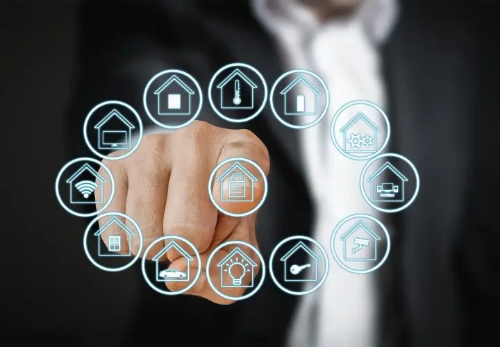 Dedo señalando iconos de casas que representan que es la domotica: seguridad, clima, luces, coche, wifi, TV, etc.