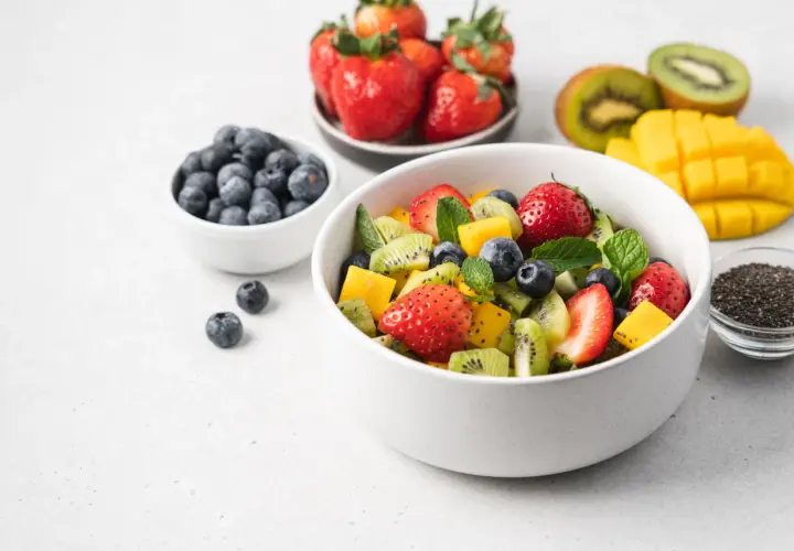 Kolorowa sałatka owocowa z truskawkami, kiwi, mango i borówkami. Idealna na zdrową przekąskę, zawiera owoce o niskim indeksie glikemicznym.