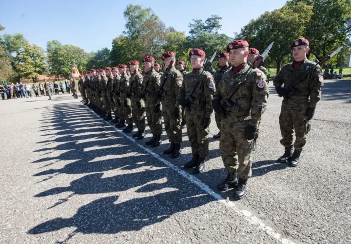 Chorąży w wojsku stoi na apelu w pełnym rynsztunku, gotowy do służby.