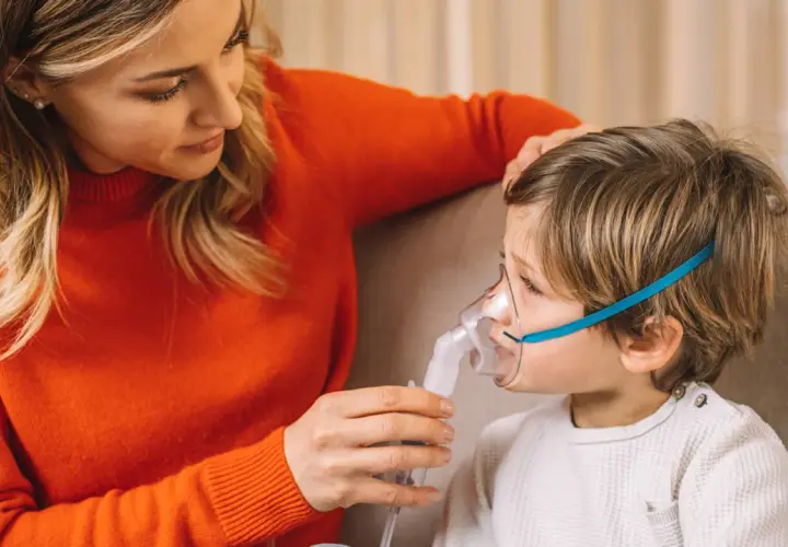 Mamma assiste il bambino con inalatore per il broncospasmo.