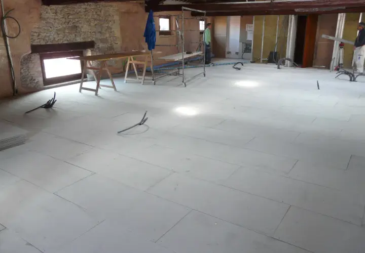 Pannelli per insonorizzare il pavimento in fase di posa, con tubi e attrezzature da cantiere.