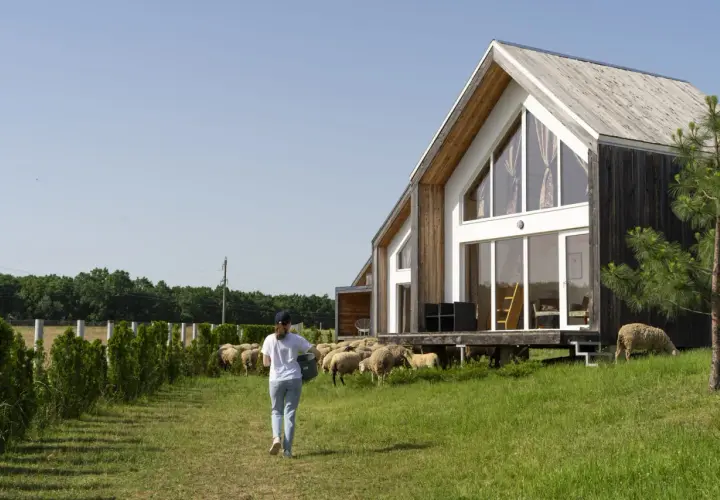 Maison ossature bois avec une femme et des moutons. Le schéma de fondation est invisible.