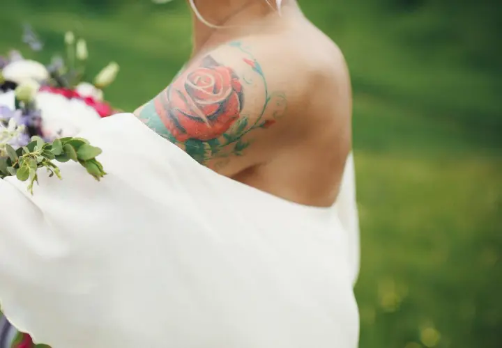 Ramię z tatuażem róży i liści, symbolizującym znak zodiaku Panna.