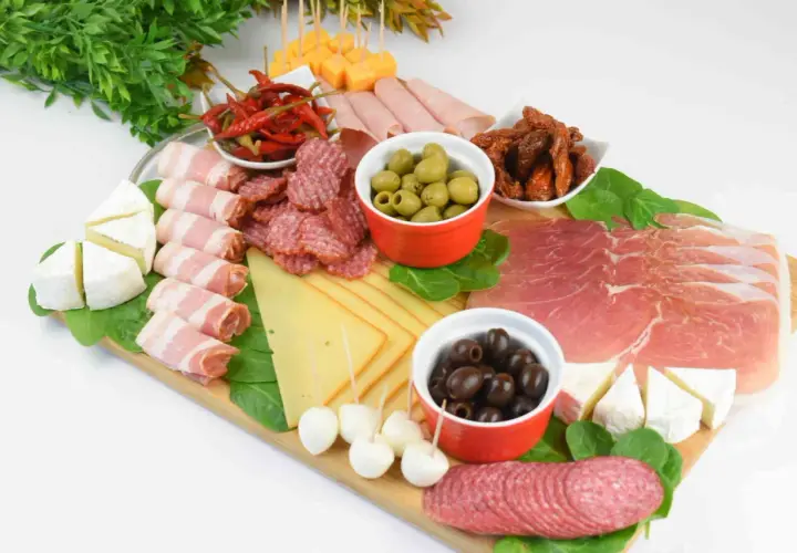 Patera wędlin i serów: salami, szynka, prosciutto, sery, oliwki, suszone pomidory i papryczki chili.