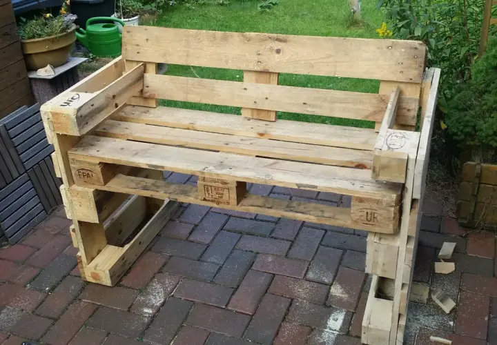 Ein selbstgebautes Palettensofa steht auf einer Terrasse. Die Sitzfläche und Rückenlehne sind aus Holzpaletten gefertigt.