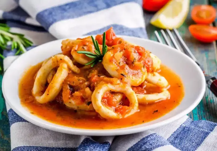 Anelli di calamari in umido con pomodoro e rosmarino, un piatto saporito e invitante.