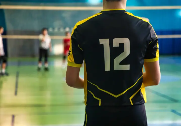 Męski strój siatkarski z numerem 12 na plecach. Zawodnik gotowy do gry na boisku.