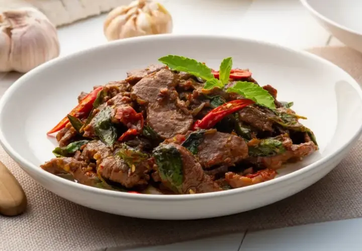Aksamitne kawałki wołowiny z bazylią i papryczką chili, aromatyczne wołowina po tajsku, podane w białej misce.