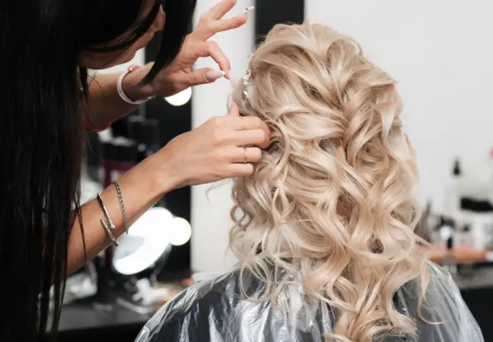 Fryzjer po hiszpańsku, czyli "peluquero", tworzy piękną fryzurę ślubną z blond loków.