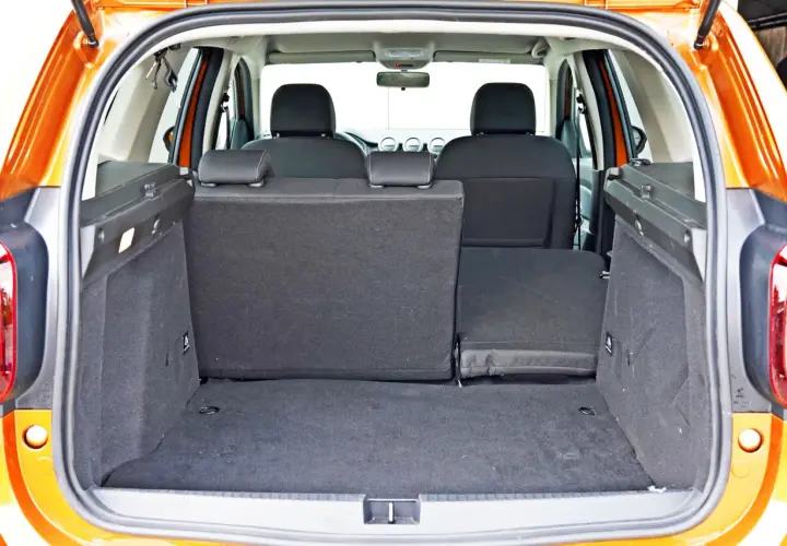 Pusty bagażnik Dacia Duster z opuszczonymi siedzeniami, gotowy na podróż.