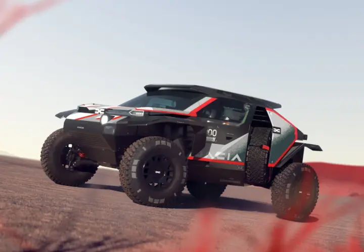 Un Dacia Sandrider nero e rosso sfreccia su un terreno sabbioso, pronto per l'avventura nel deserto.