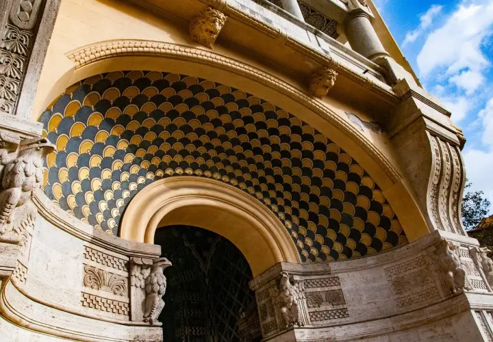 Dettaglio architettonico con decorazioni a squame dorate e blu, sculture di aquile e teste leonine. Un esempio di architettura del quartiere Coppedè.
