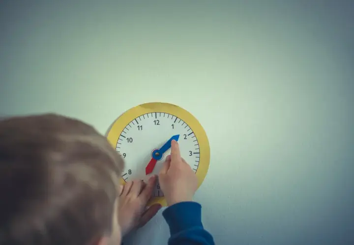 Dziecko uczy się odczytywać godzinę na zabawkarskim zegarze. Prosta nauka zegara to świetna zabawa!