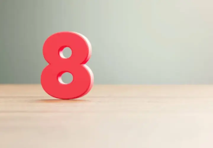 Número 8 rojo sobre superficie de madera, simbolizando el significado número 8 en lo espiritual: abundancia, equilibrio y poder infinito.