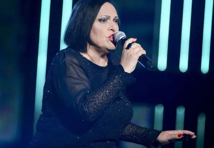 Grażyna Łobaszewska śpiewa swoje utwory na scenie, w czarnej, błyszczącej sukni.