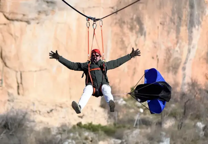 Hombre disfrutando de una tirolina de cuenca, con los brazos extendidos y una gran sonrisa, mientras desciende por un acantilado.