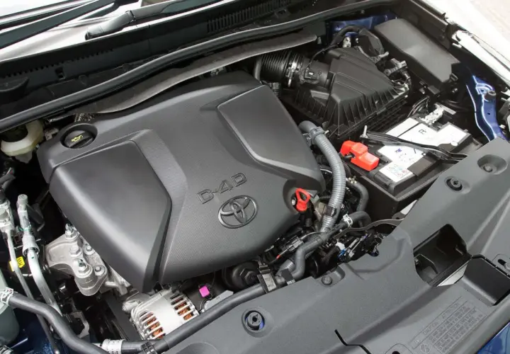 Silnik D-4D w Toyota Avensis T27. Widoczny jest czarny plastikowy dekiel silnika z logo Toyoty i napisem D-4D, akumulator oraz elementy układu dolotowego.