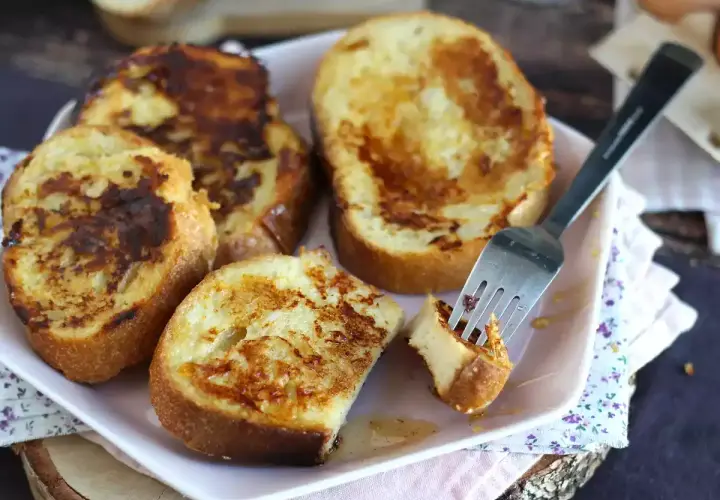 Un plat de pain perdu salé, doré et appétissant, avec une fourchette piquant un morceau. Un délice pour le petit-déjeuner ou le brunch.