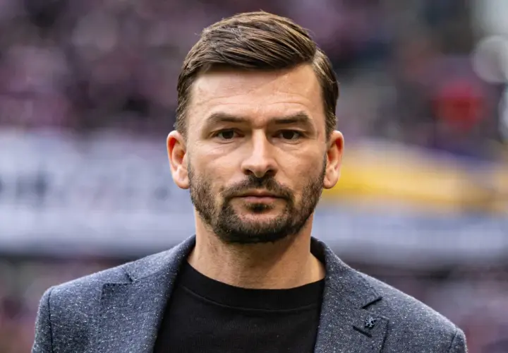 Górnik Zabrze trener, w eleganckim garniturze, patrzy prosto w obiektyw.