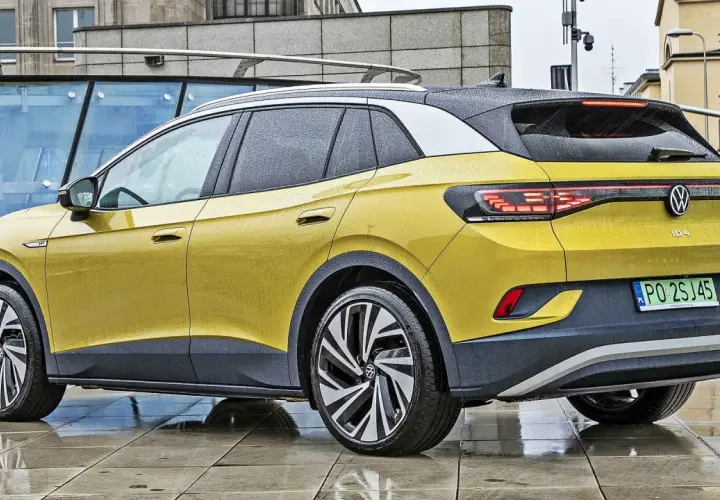 Żółty VW ID.4 z czarnym dachem i felgami stoi na mokrym chodniku.