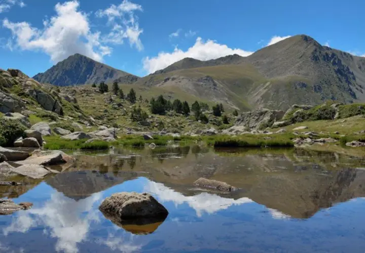 Reflejo de montañas y nubes en un lago sereno del valle de Madriu-Perafita-Claror.