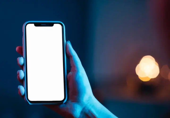Dłoń trzyma smartfon z pustym ekranem **AMOLED**, otoczony niebieskim i czerwonym światłem.