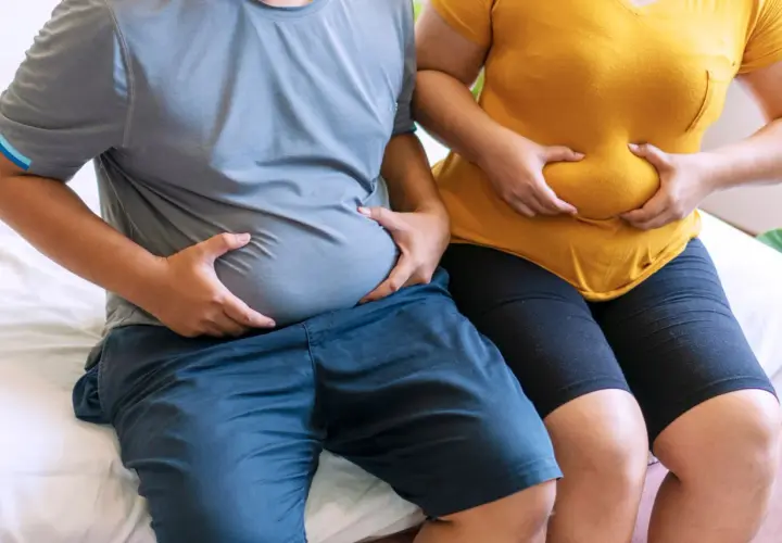 Osoby z nadwagą trzymają się za brzuchy. Zastanawiają się, czy bieżnia odchudza brzuch.