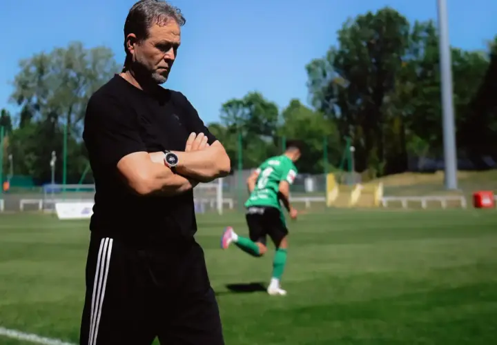 Trener Górnika Łęczna z rękami skrzyżowanymi na piersi obserwuje trening.